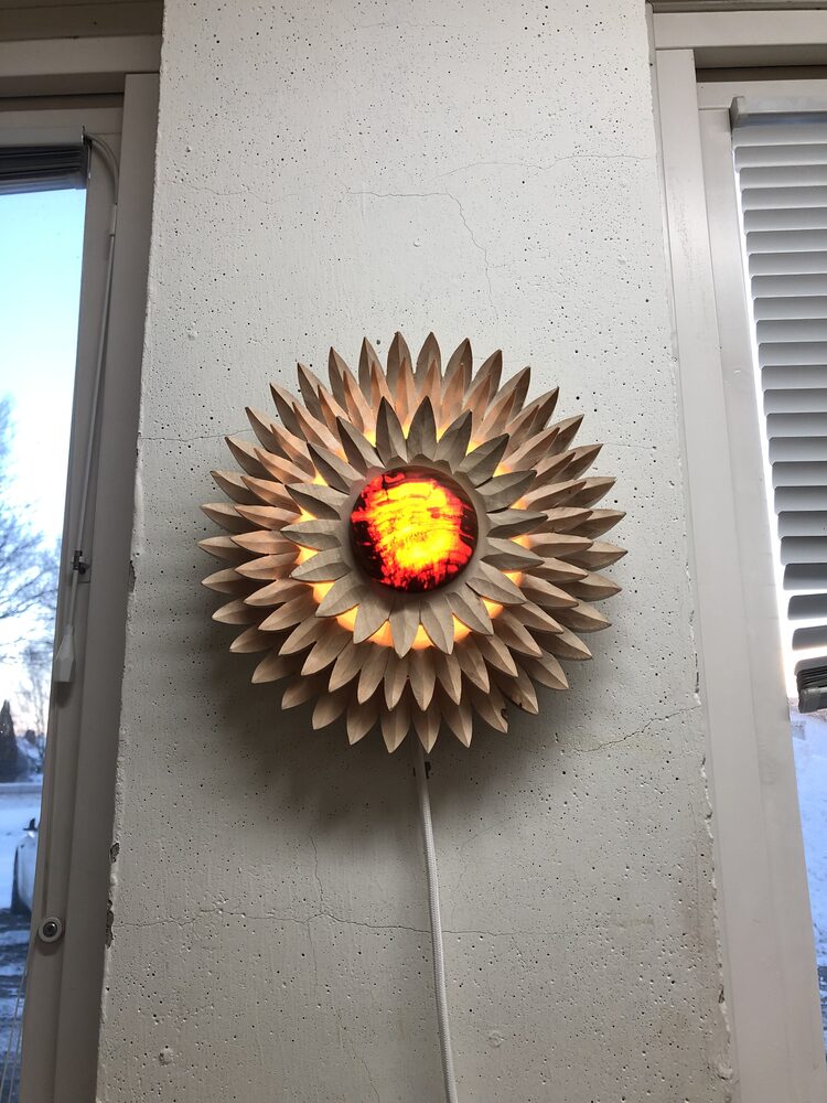 Vägglampa i lind med ljuset på